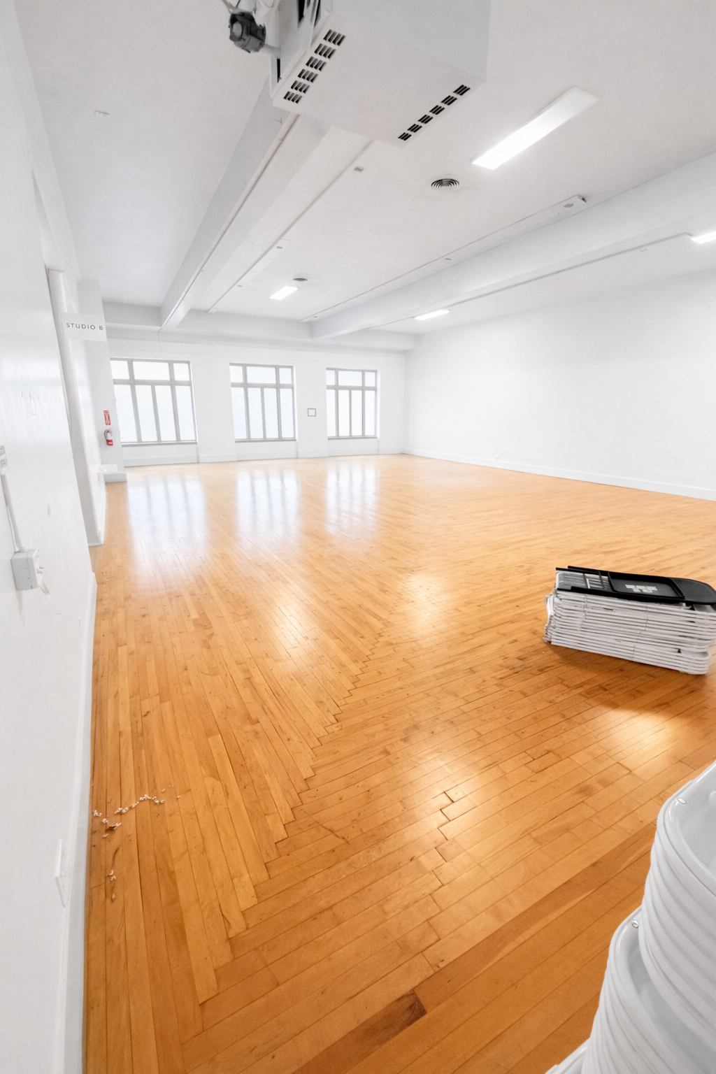 Bright open hardwood floor event space at OnDemand Creative Studios with stacked chairs ready for setup